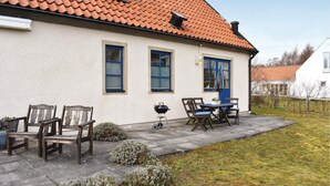 A house with a tiled roof, a patio with outdoor furniture, and a small garden area. - Amazing home in Borrby with WiFi (Borrby)