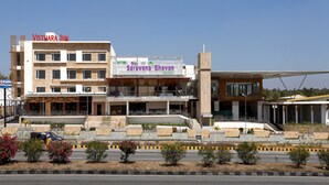 A multi-story building with signage for 'Vishthara Inn' and 'Saravana Bhavan'.