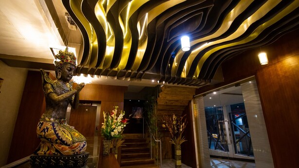 A statue in a lobby with a modern ceiling design.