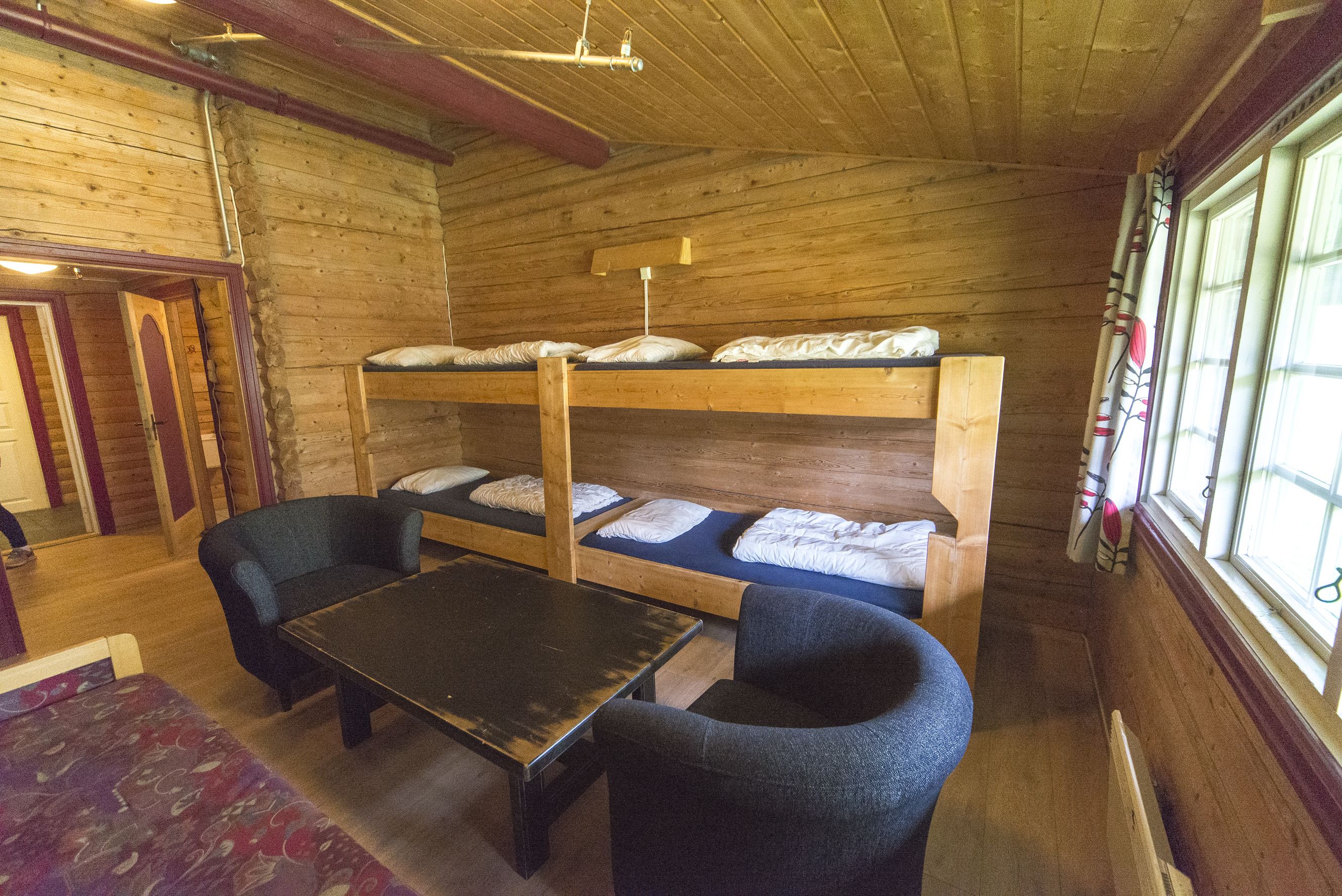 Une cabane en bois avec des lits superposés, une table et deux chaises.