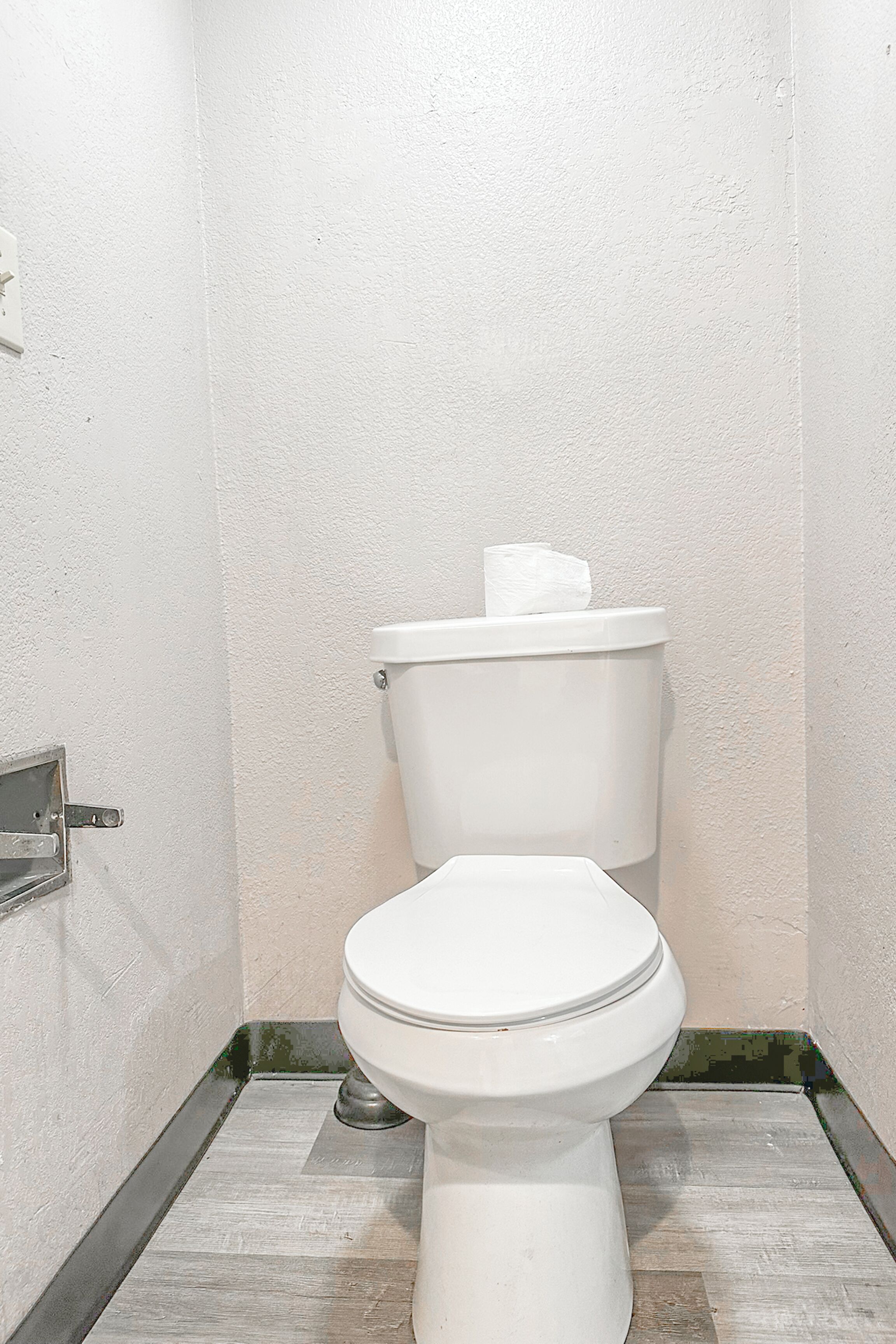 A white toilet in a bathroom with a tiled floor and a white wall.