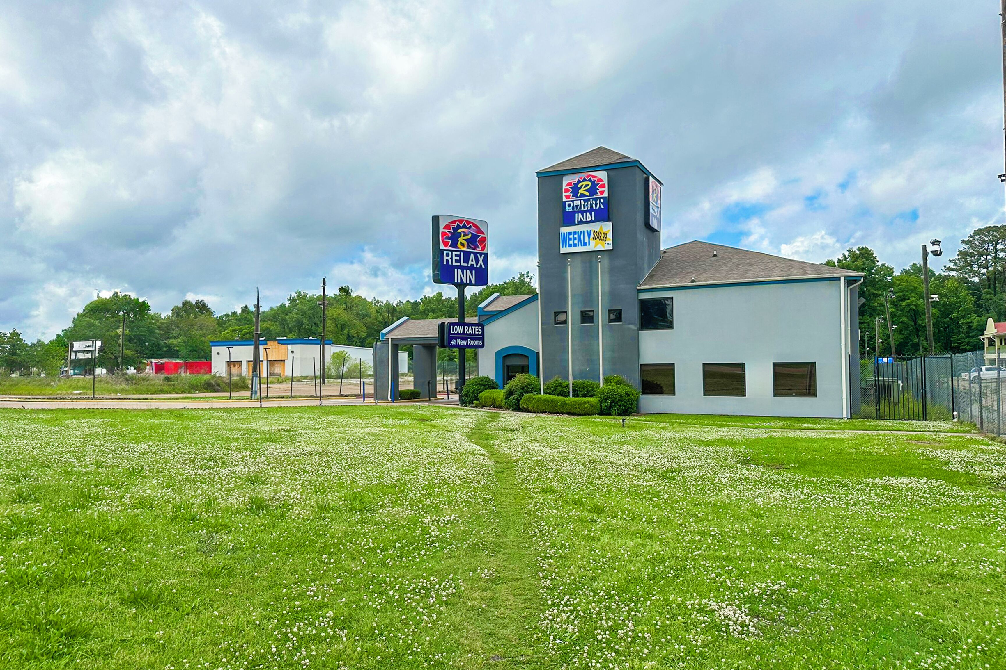 A hotel with a Relax Inn sign, a Weekly $100 rate sign, and a Low Rates sign.