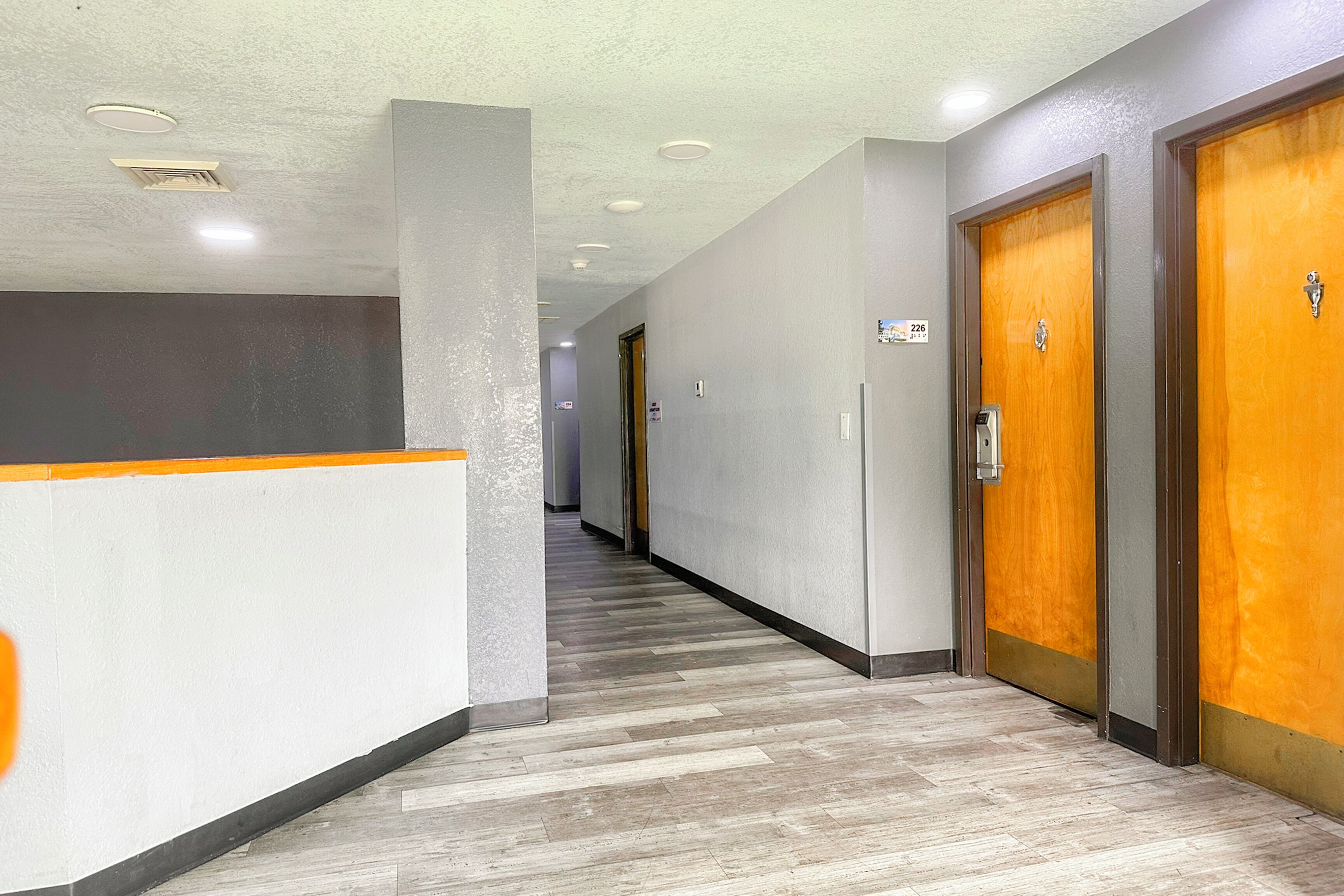 A hallway with wooden doors, a reception desk, and a tiled floor.