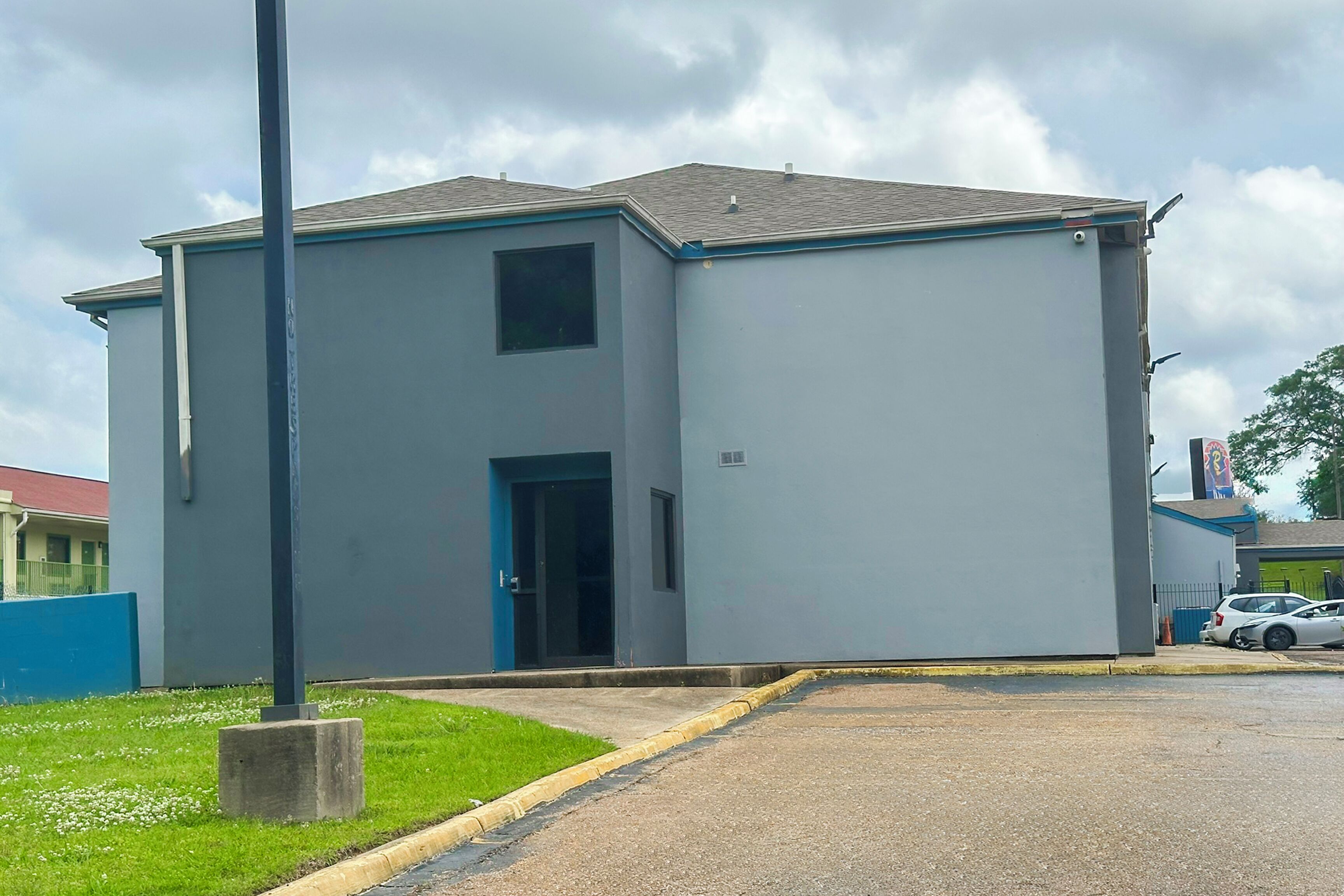 Un edificio de dos pisos con techo plano y puerta azul.