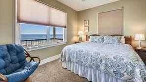 A bedroom with a large bed, two bedside lamps, a chair, and a ceiling fan. - ANGEL WING is a lovely home offering open living spaces and privacy (St. George Island)