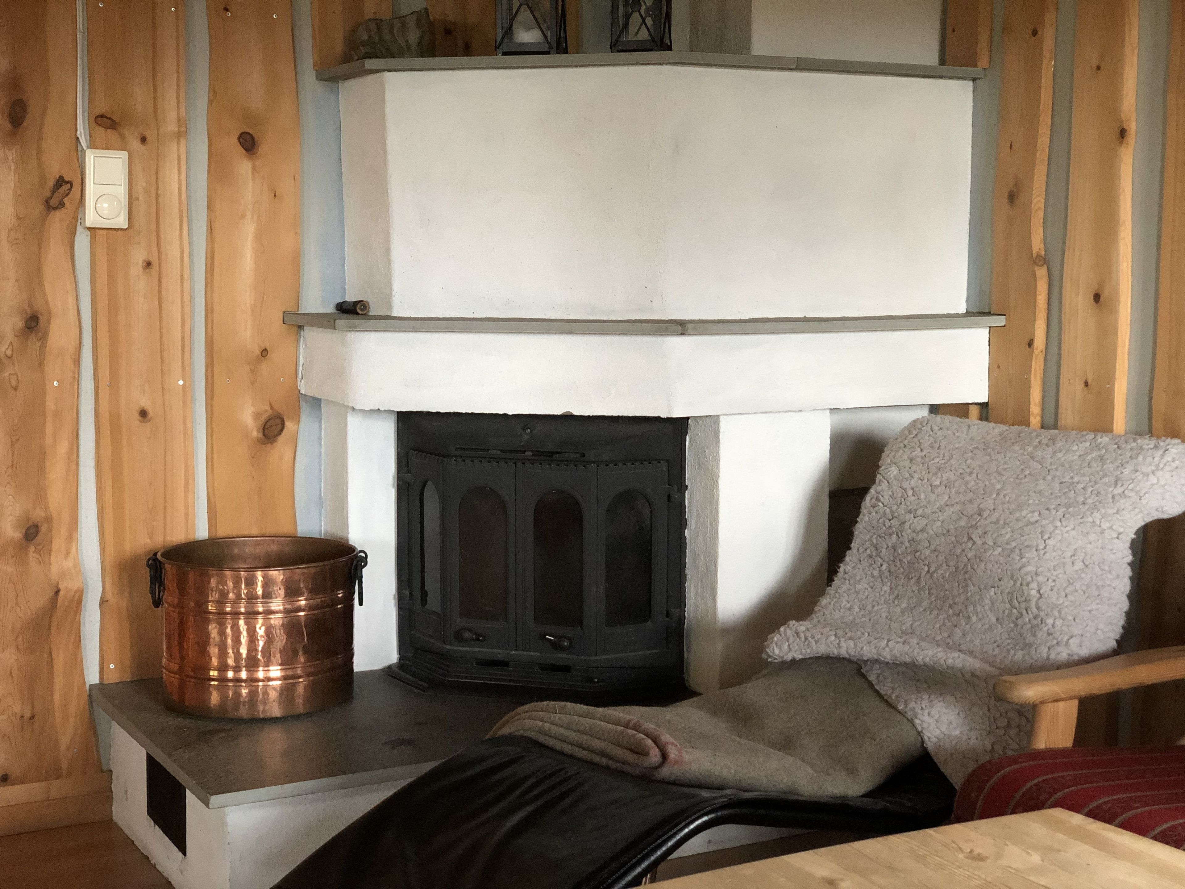 A cozy room with a fireplace, a wooden chair, and a copper pot.