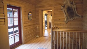 A wooden interior with a red-framed door, a mirror, and a fur piece on the wall. - Hytter Dombås (Dovre)