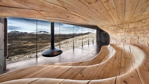 A modern interior with wooden walls and a curved bench. - Hytter Dombås (Dovre)