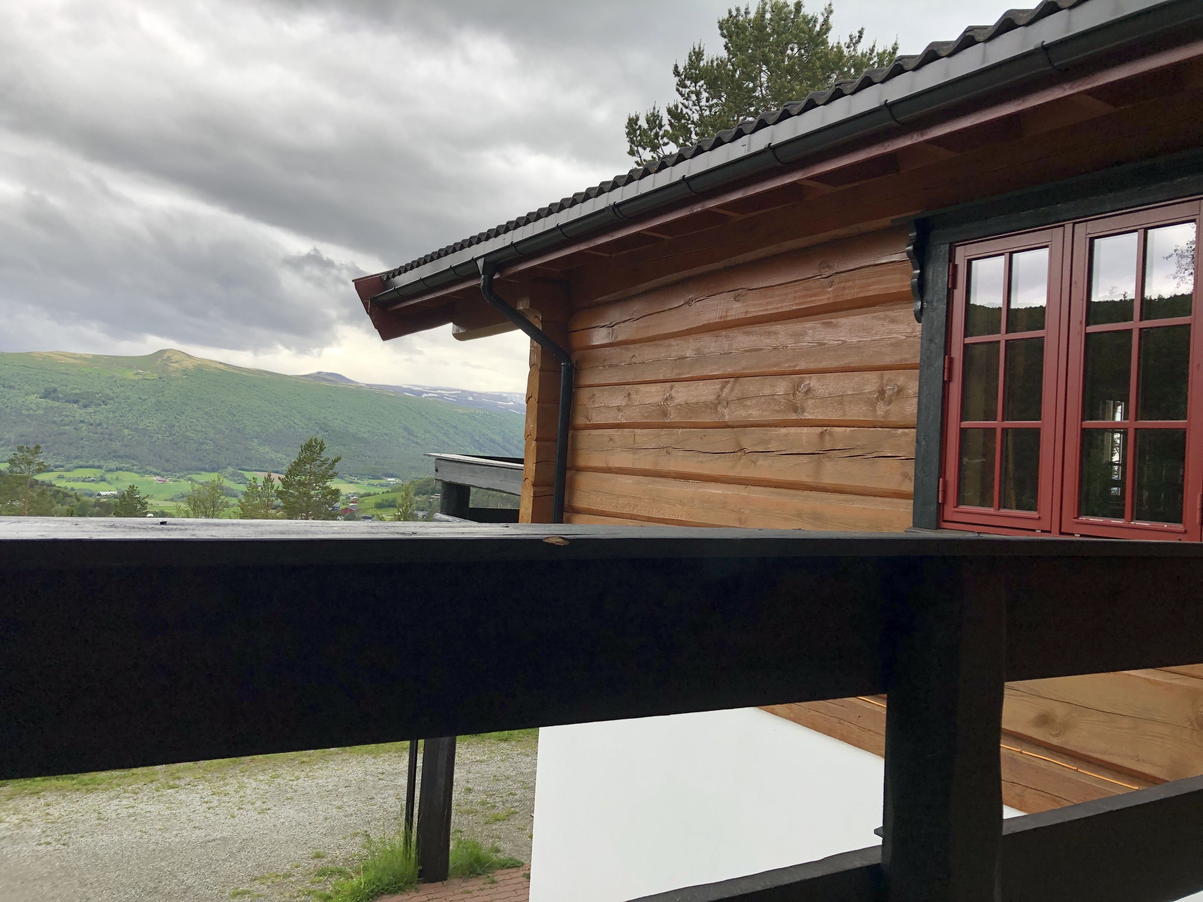 A wooden cabin with a balcony overlooking a mountainous landscape.