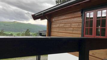 A wooden cabin with a balcony overlooking a mountainous landscape.