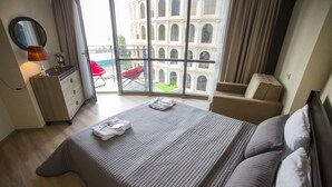 Une chambre d’hôtel avec un grand lit, un bureau avec une lampe, une chaise et une vue sur un immeuble par la fenêtre.
