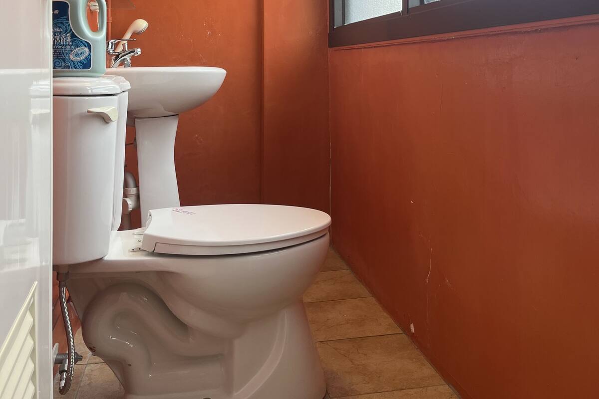 Une salle de bain avec des toilettes, un lavabo et une fenêtre.