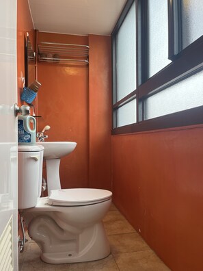 Un baño con inodoro, lavamanos y ventana.