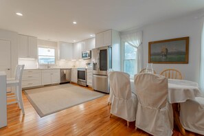 Enjoy meals in the spacious kitchen and dining area, featuring a large window, appliances, and a beautiful painting.