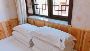 Cama bem arrumada com lençóis brancos em quarto com painéis de madeira e janela com design em grade.