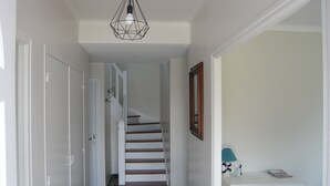 A hallway with a staircase, a door, a small table with a lamp, and a framed picture on the wall. - Country house 5 kms from the sea, 12 kms from Perros Guirec.  (Trelevern)