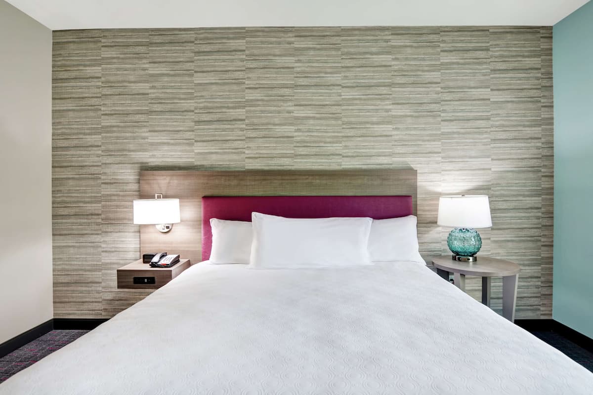 Une chambre d’hôtel avec un grand lit, deux tables de chevet et un mur à texture.