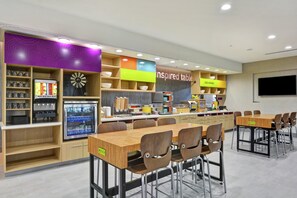 A modern cafeteria with multiple seating areas, a self-service beverage station, and a variety of food options. - Home2 Suites by Hilton Pecos (Pecos)