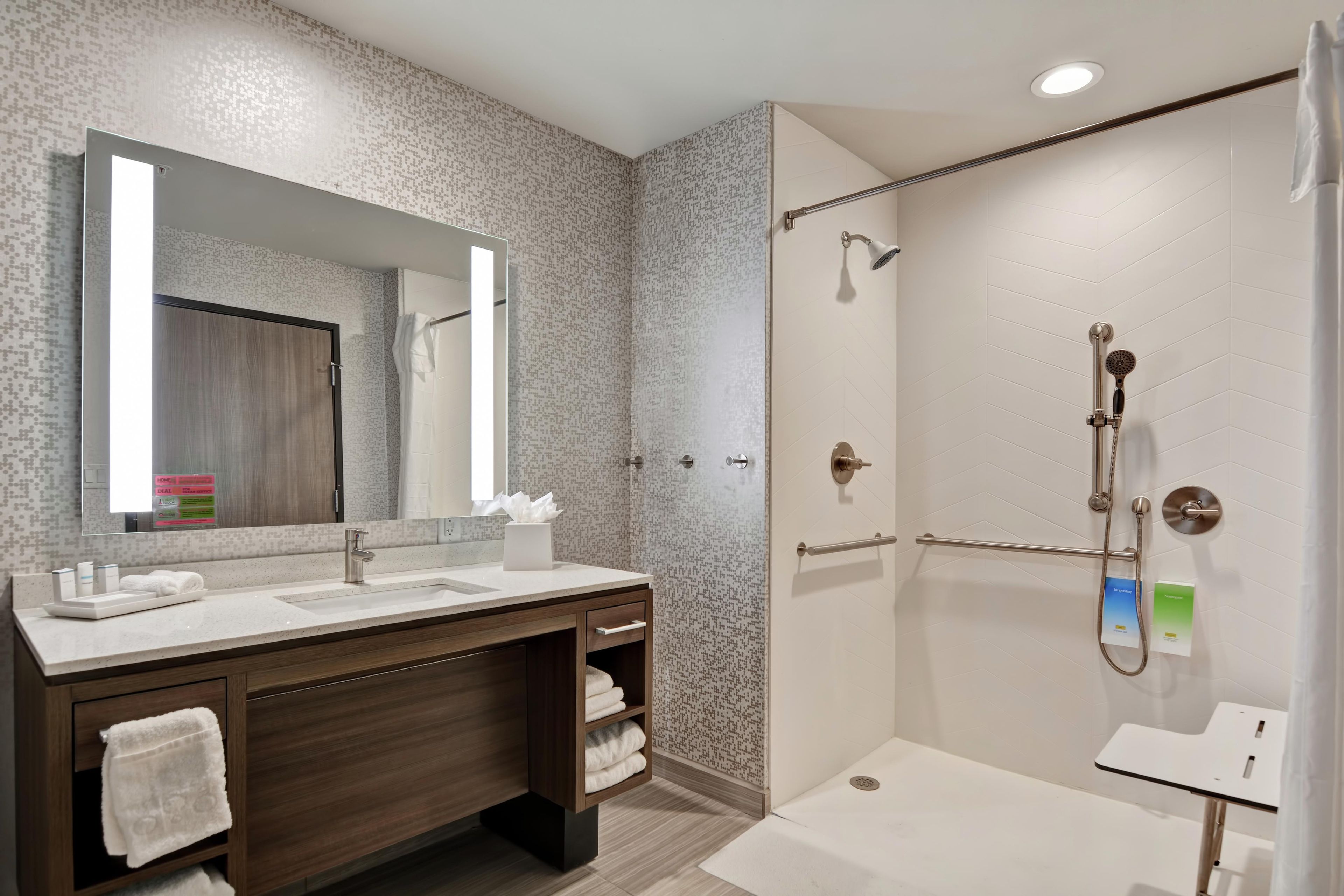 Un baño moderno con ducha, tocador con espejo y perchero.