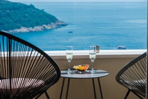 A table with two glasses of water and a bowl of fruit, overlooking a coastal view. - Apartments Horizon (Dubrovnik)