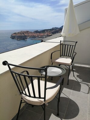 A balcony with two chairs and a table, overlooking a coastal town and the sea. - Apartments Horizon (Dubrovnik)