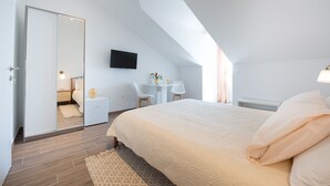 A modern bedroom with a large bed, a desk, a chair, and a TV on the wall. - Apartments Horizon (Dubrovnik)