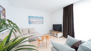A modern living room with a sofa, a coffee table, a TV stand, and a painting on the wall. - Apartments Horizon (Dubrovnik)