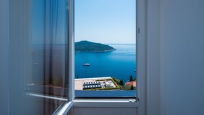 A view from a window overlooking a coastal area with a boat and buildings. - Apartments Horizon (Dubrovnik)
