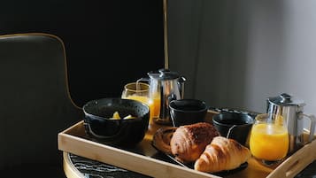 Bandeja de desayuno con cruasanes, jugo de naranja y café sobre una mesa de mármol en una habitación de hotel.