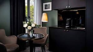 A modern kitchen with dark cabinetry, a marble countertop, and a small dining area with two chairs and a table.