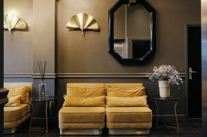 A modern lobby with a two-seater sofa, a mirror, and decorative wall panels.