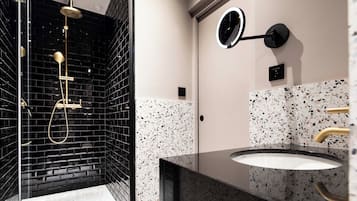 A modern bathroom with a black-tiled shower area and a granite countertop sink.