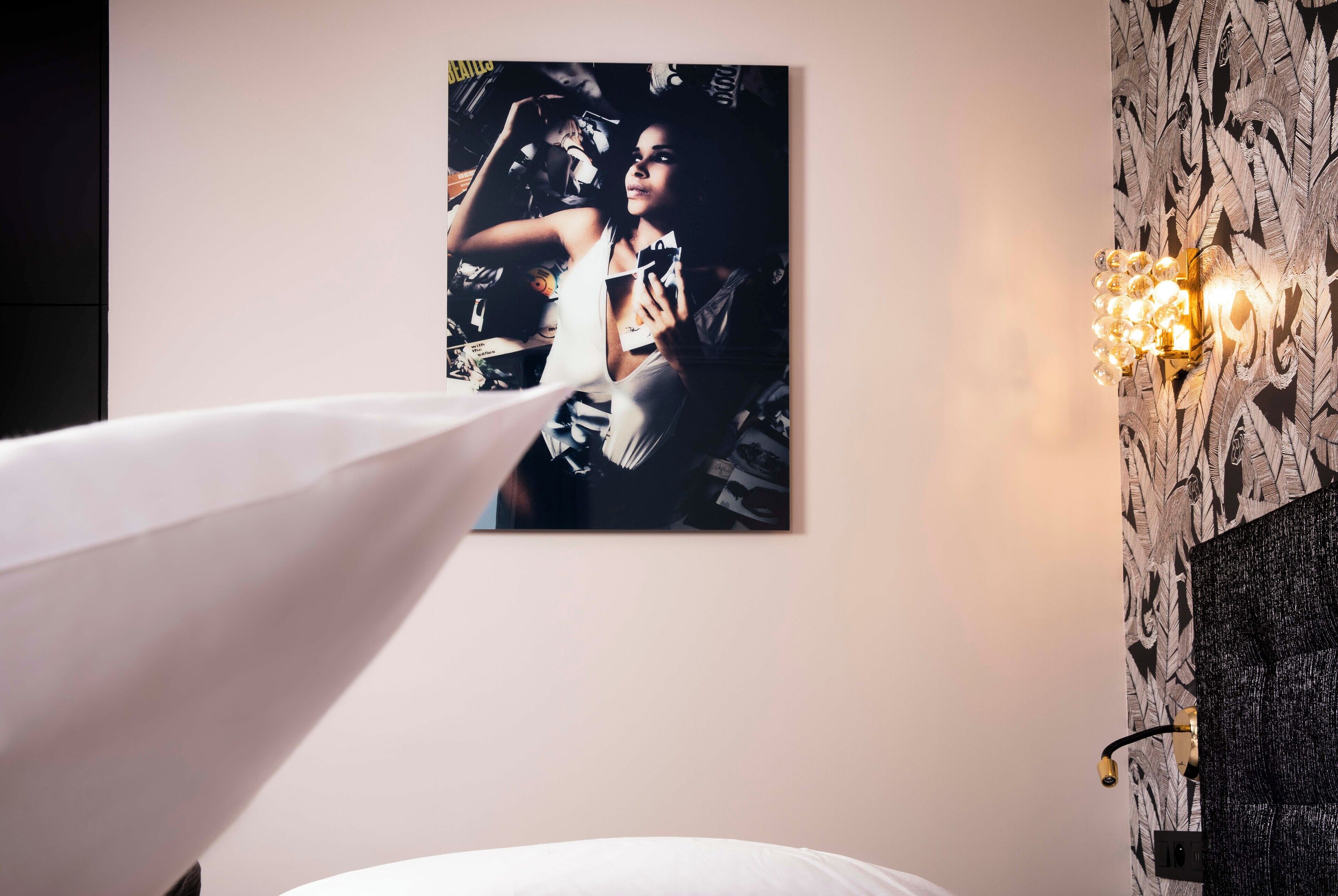 A room with a bed, a wall-mounted picture, and a decorative light fixture.