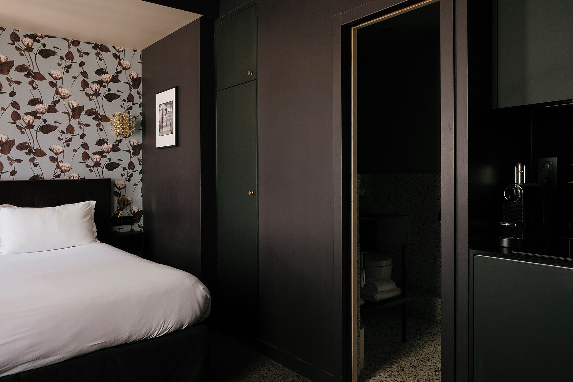 Une chambre d’hôtel comprenant un lit, une armoire, une petite salle de bain et un mini-bar.