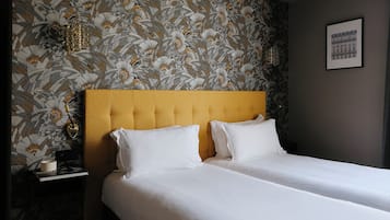 Ein Hotelzimmer mit einem Bett, einem Nachttisch und einer Wand mit Blättermotiv.