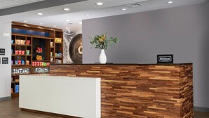A hotel reception desk with a wooden design, a white counter, and a sign indicating 'Hilton Honors'. - Hampton Inn & Suites Pittsburgh New Stanton (New Stanton)