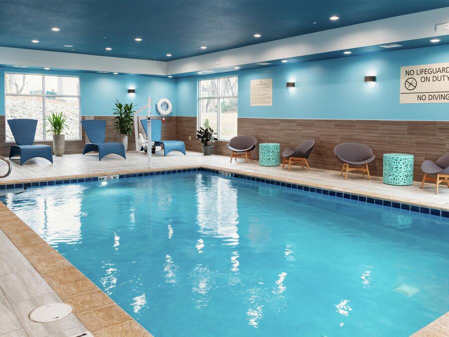 A swimming pool with lounge chairs and a lifeguard sign.