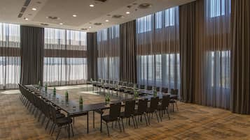 A conference room with long tables, chairs, and green bottles.