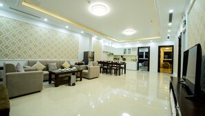 A spacious living room with a sofa, coffee table, and TV. - The Shine Office and Apartment (Hai Phong)