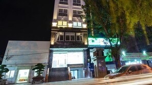 A multi-story building with illuminated signage at the top, a visible entrance with steps, and a car parked in front. - The Shine Office and Apartment (Hai Phong)