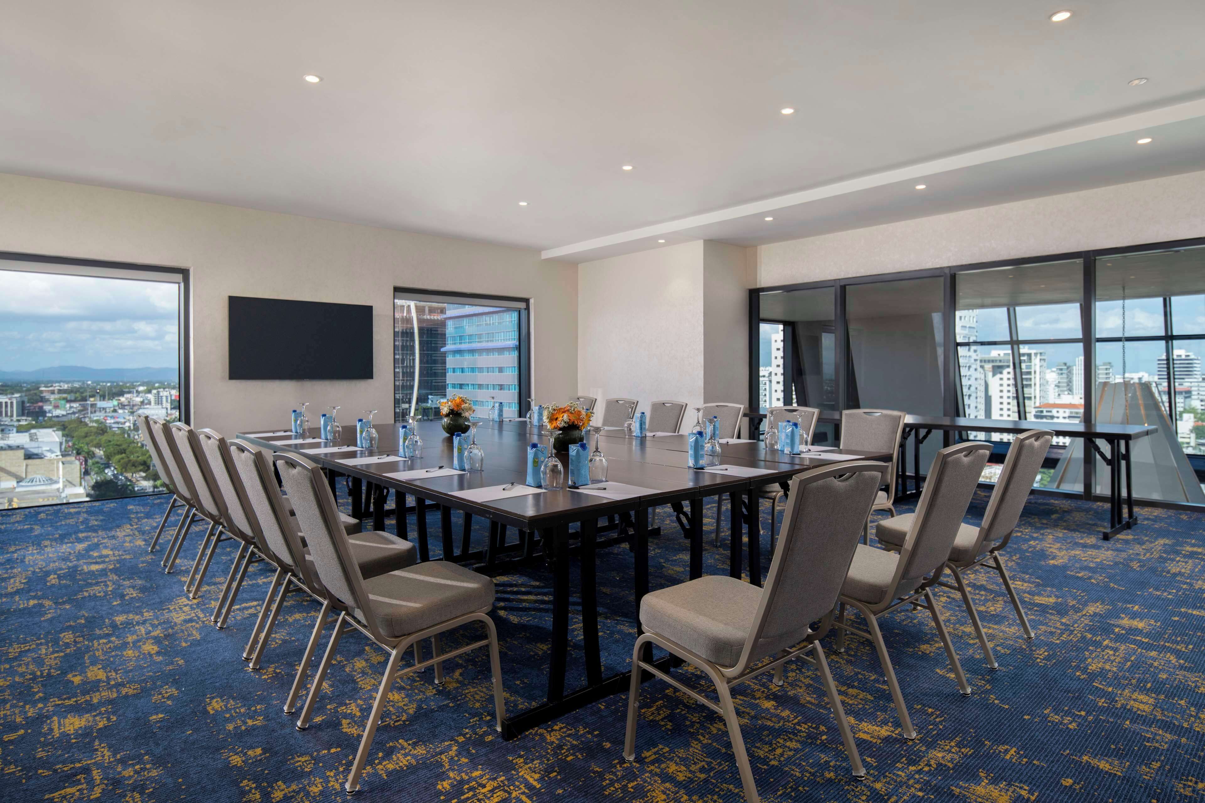 A conference room with a large table, chairs, and a city view.