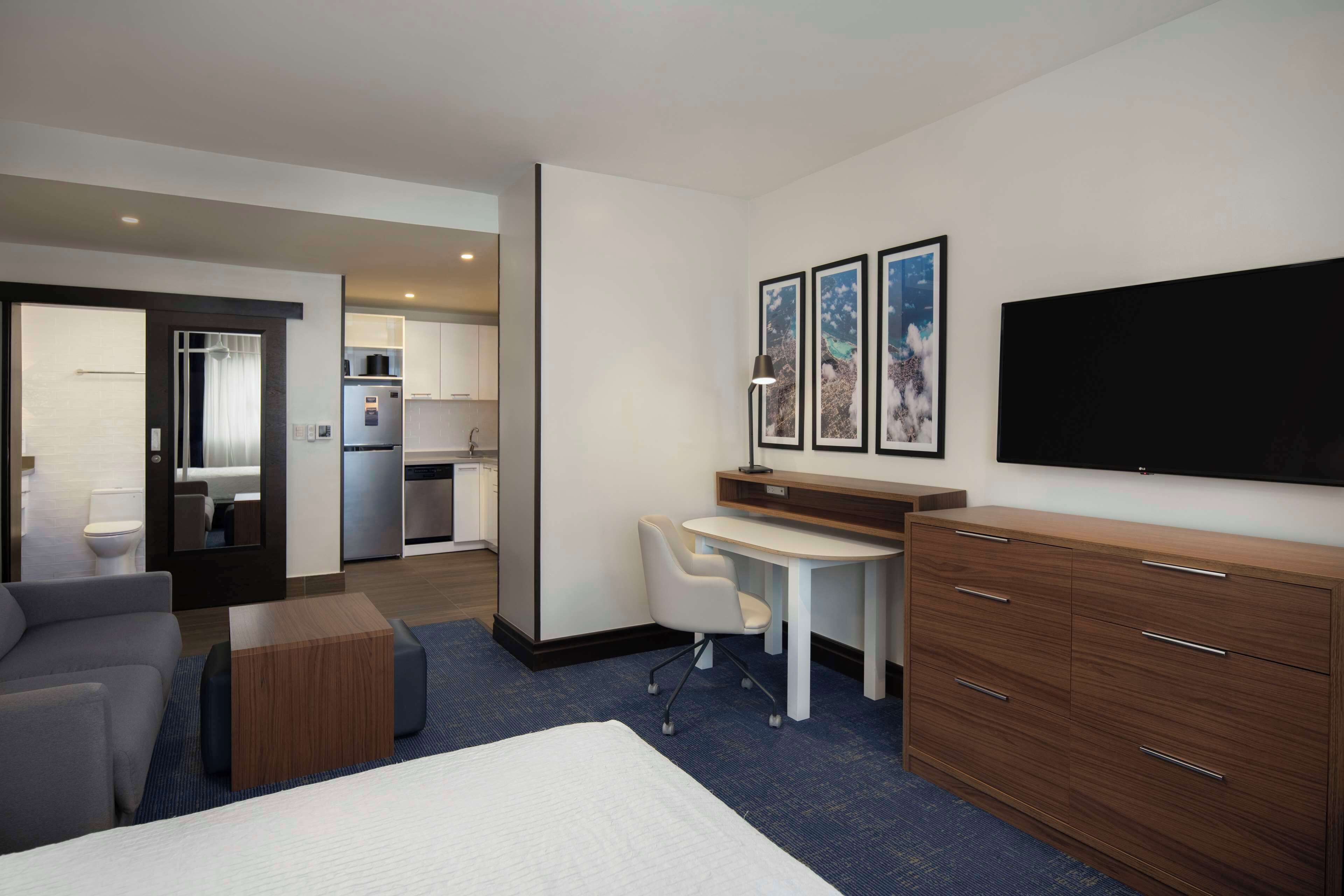 Una habitación de hotel con cama, escritorio, silla, armario y televisor.