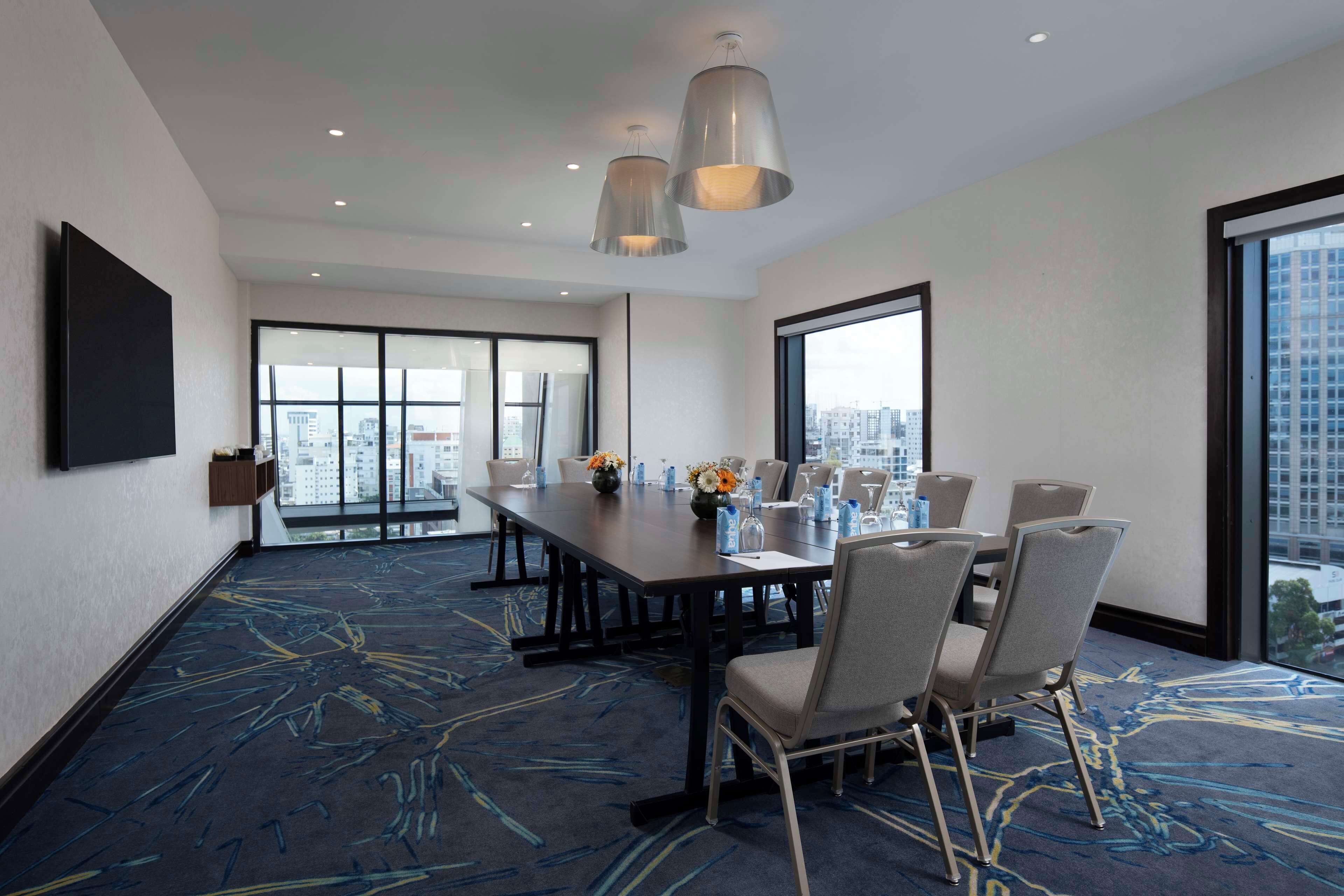 A conference room with a large table, chairs, and a city view through large windows.