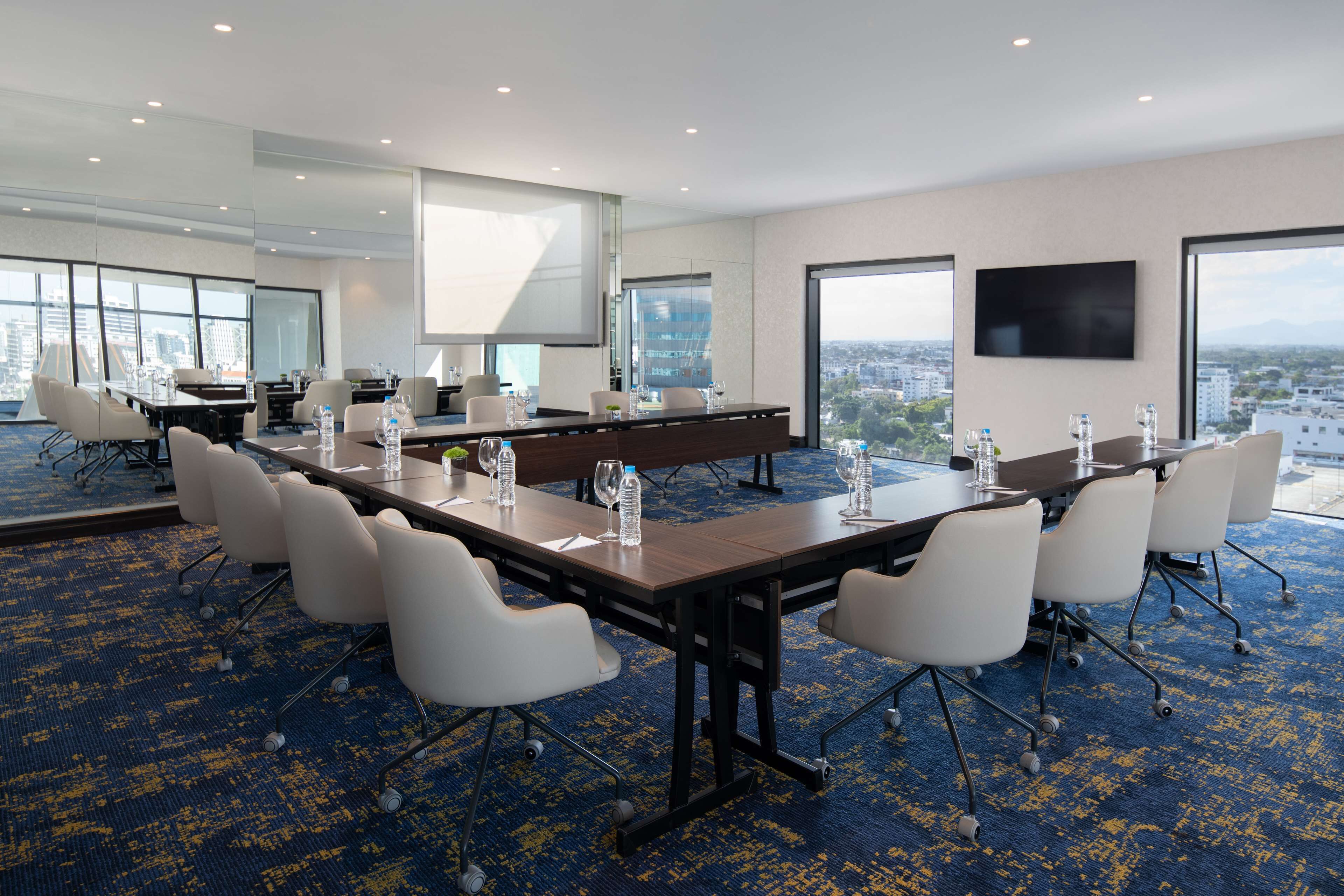 A conference room with a long table, white chairs, and a city view.