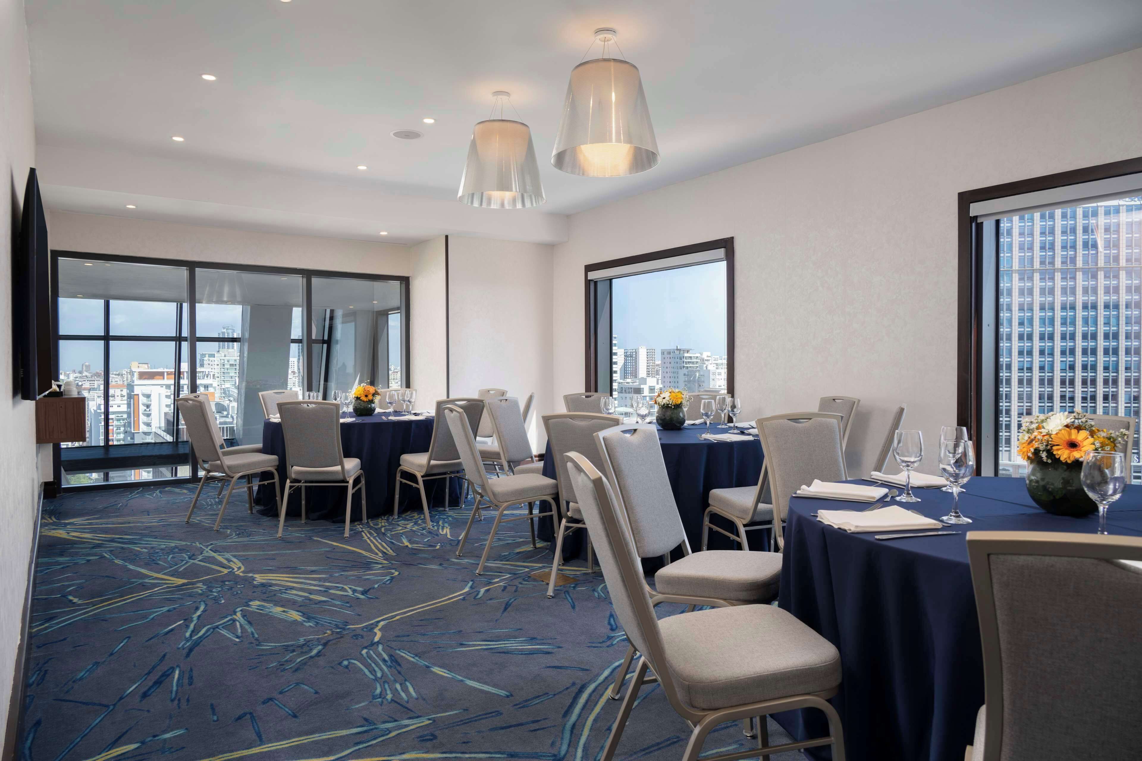 A conference room with round tables, chairs, and a city view.