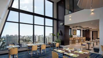 A modern dining area with large windows, high ceilings, and a city view.