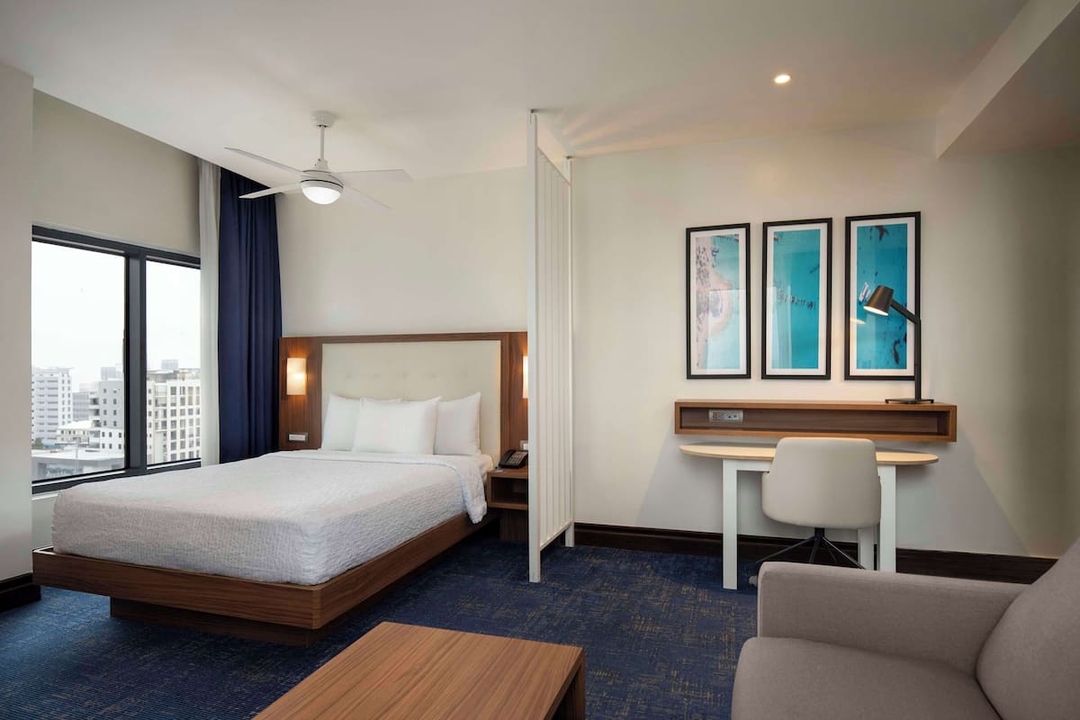 Ein Hotelzimmer mit Bett, Schreibtisch, Stuhl und Blick auf die Stadt.