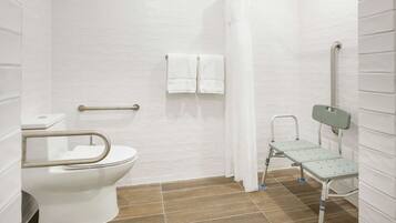 A bathroom with a white toilet, a shower with a curtain, and a grab bar.