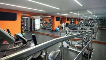 Une salle de sport équipée de tapis de course, de poids et d'appareils d'exercice.