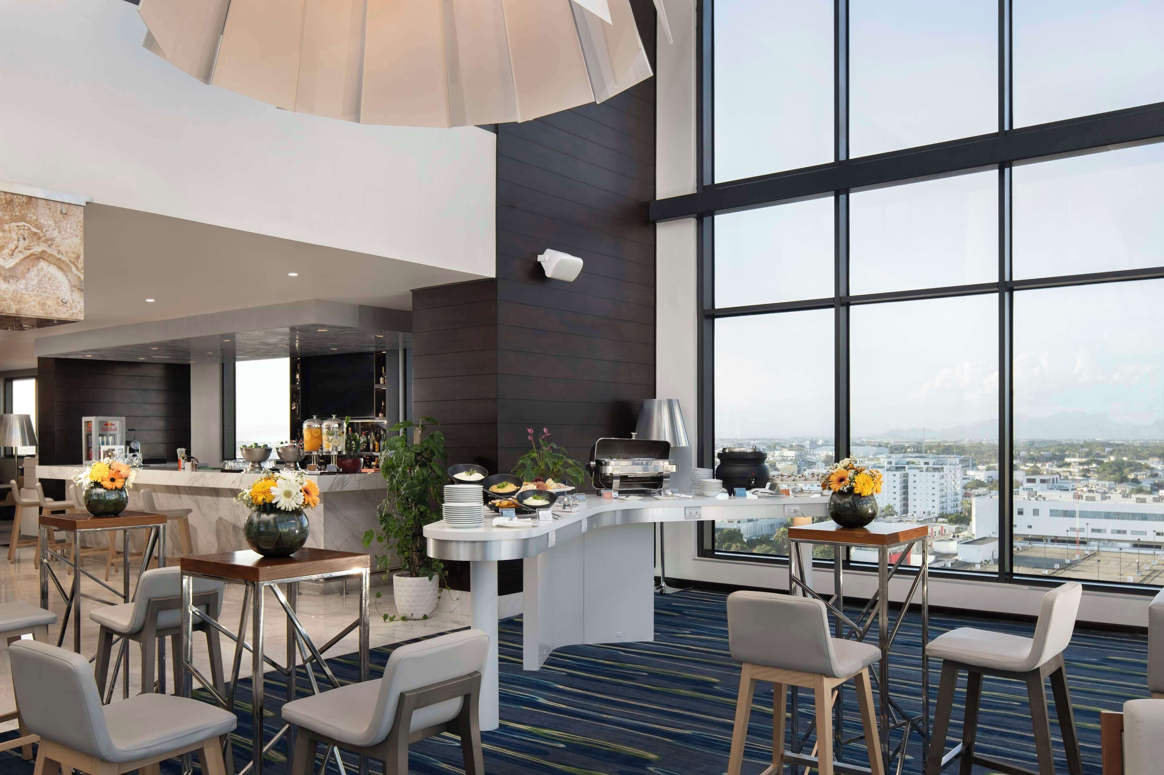 Een moderne hotelentree met een bar, zitplaatsen en grote ramen met uitzicht op de stad.